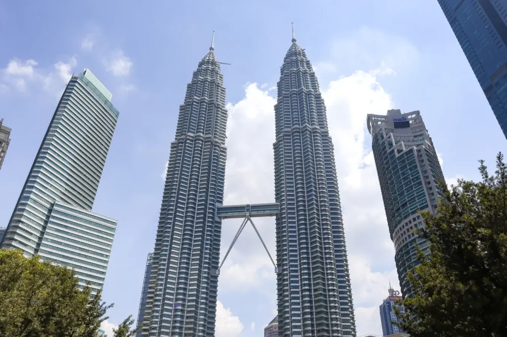 The iconic Petronas Twin Towers in Kuala Lumpur during the daytime with surrounding modern skyscrapers.