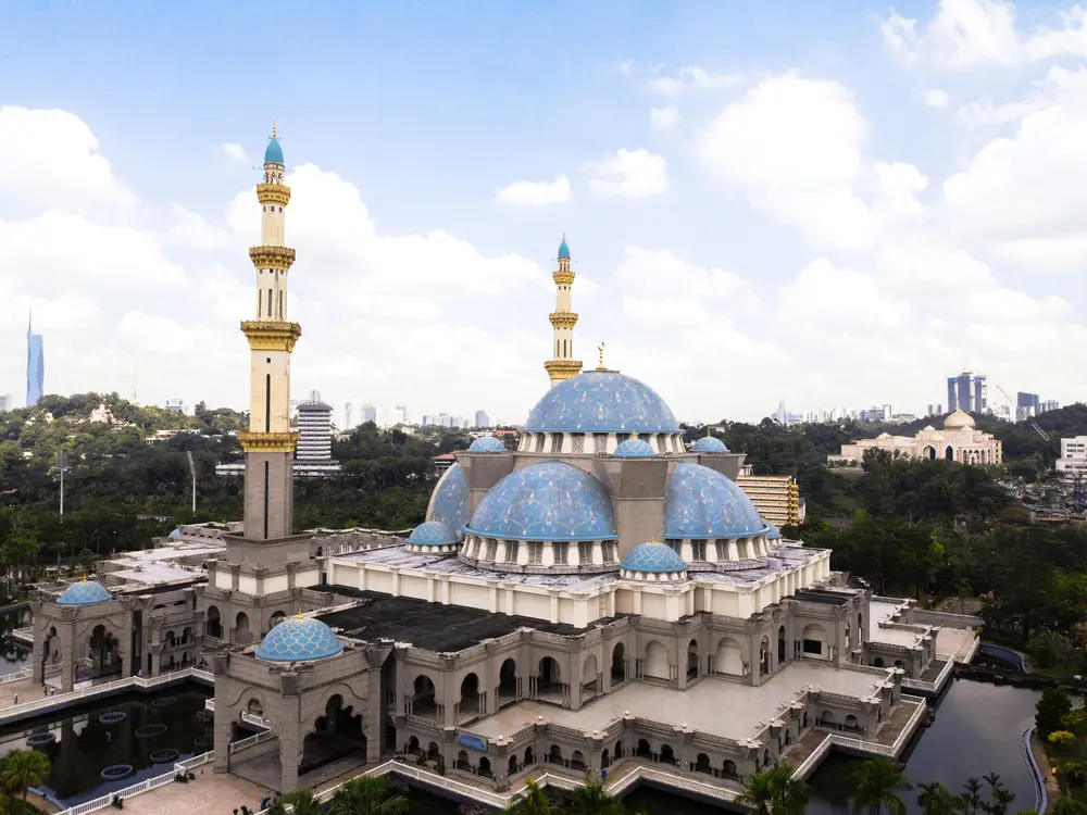 The majestic Wilayah Mosque in Kuala Lumpur with its distinctive blue domes and surrounding city landscape