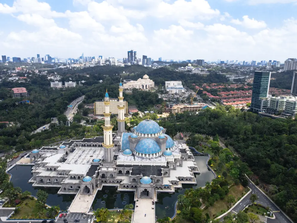 Aerial view of the Wilayah Mosque with its striking blue domes, surrounded by greenery, Kuala Lumpur.