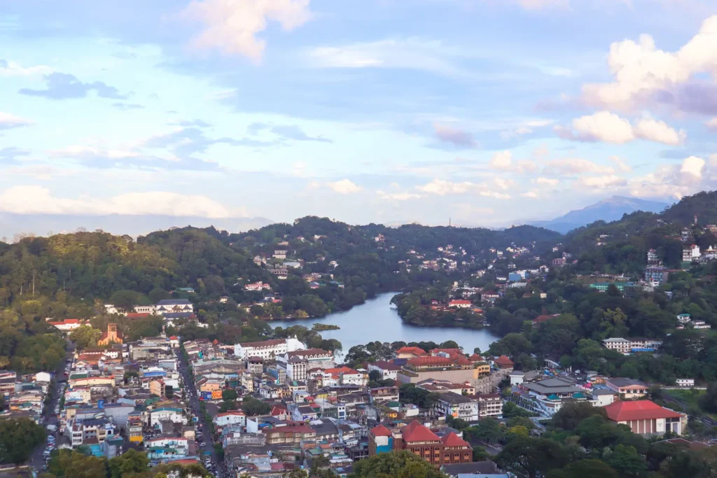 A panoramic view of Kandy city and Kandy Lake, surrounded by lush greenery and hills, taken from a vantage point near Sri Maha Bodhi Viharaya. This stunning perspective showcases what to do in Kandy for nature and photography lovers.