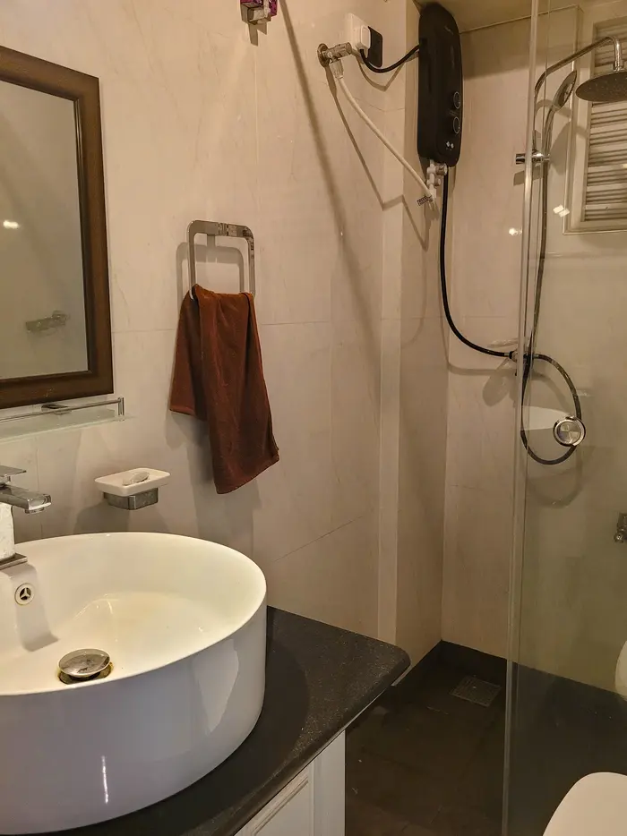 A sleek bathroom with a black countertop, a bowl-shaped sink, and a wall-mounted showerhead. This stylish design highlights the upscale features offered by hotels in Kandy.