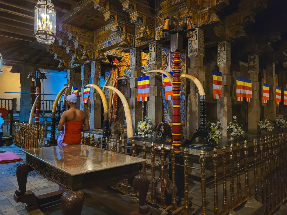 The interior of the Temple of the Sacred Tooth Relic, adorned with traditional decorations, ivory tusks, and Buddhist flags. A significant religious site and one of the must-see Kandy attractions.