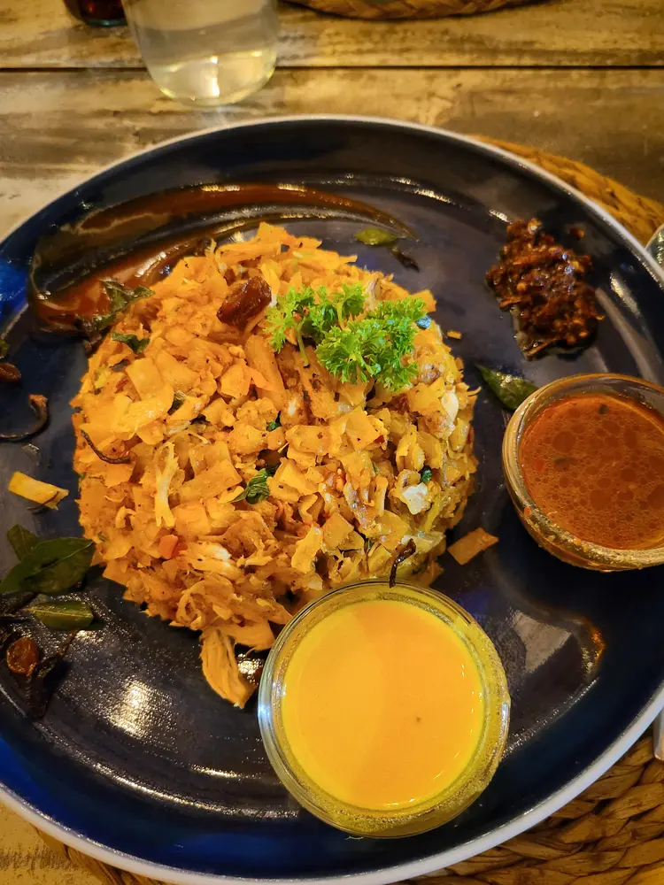 A plate of kottu roti, a Sri Lankan dish made of chopped flatbread and spiced vegetables, served with an assortment of sauces. A culinary must-try when dining in Kandy.