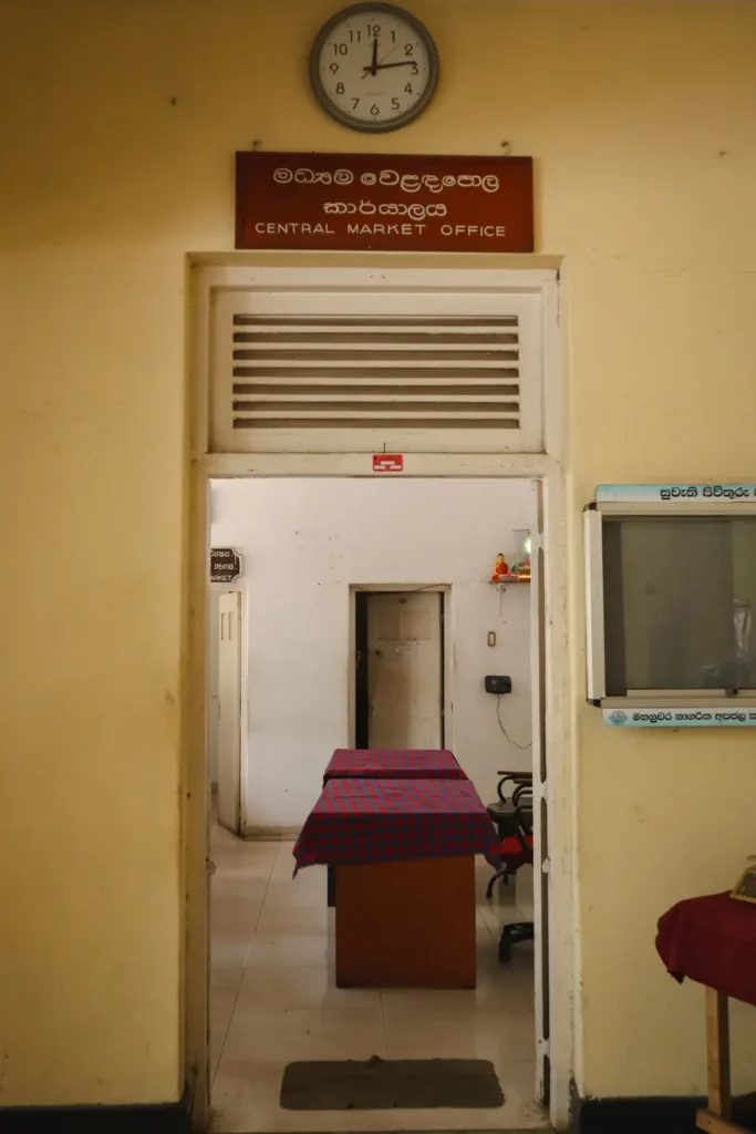 A simple office space with a clock and a sign reading "Central Market Office" in English and Sinhala. A glimpse into the administrative area of Kandy’s bustling Central Market.