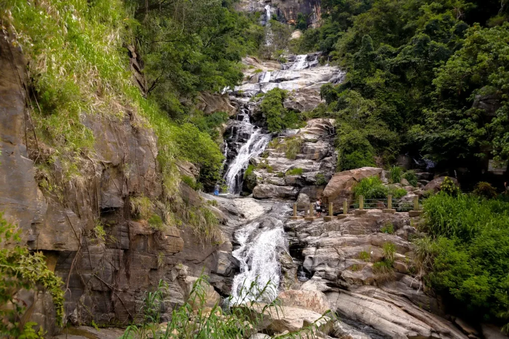 A stunning view of Ravana Falls in Ella, Sri Lanka, cascading over rocky terrain amidst lush forest