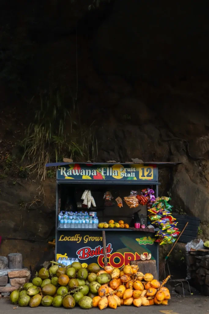 A local fruit stall near Ravana Falls in Ella, Sri Lanka, selling fresh coconuts, water bottles, and snacks, showcasing a unique experience among the things to do in Ella