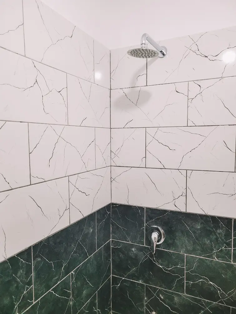 A modern bathroom in a hotel near Lake Koman, featuring white and green tiles with a clean and contemporary design