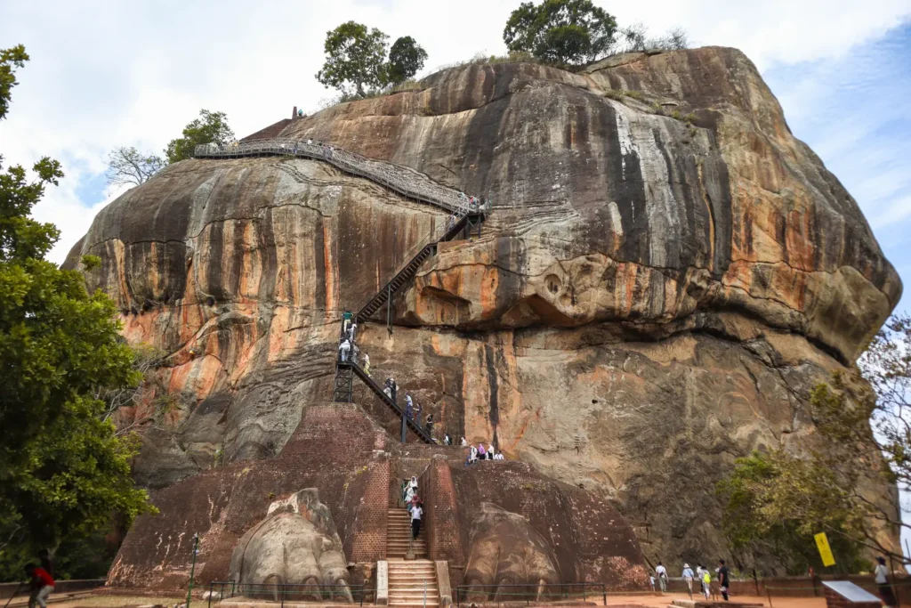 The iconic Lion Rock in Sigiriya, a massive rock formation with a steep staircase and railings leading to the top