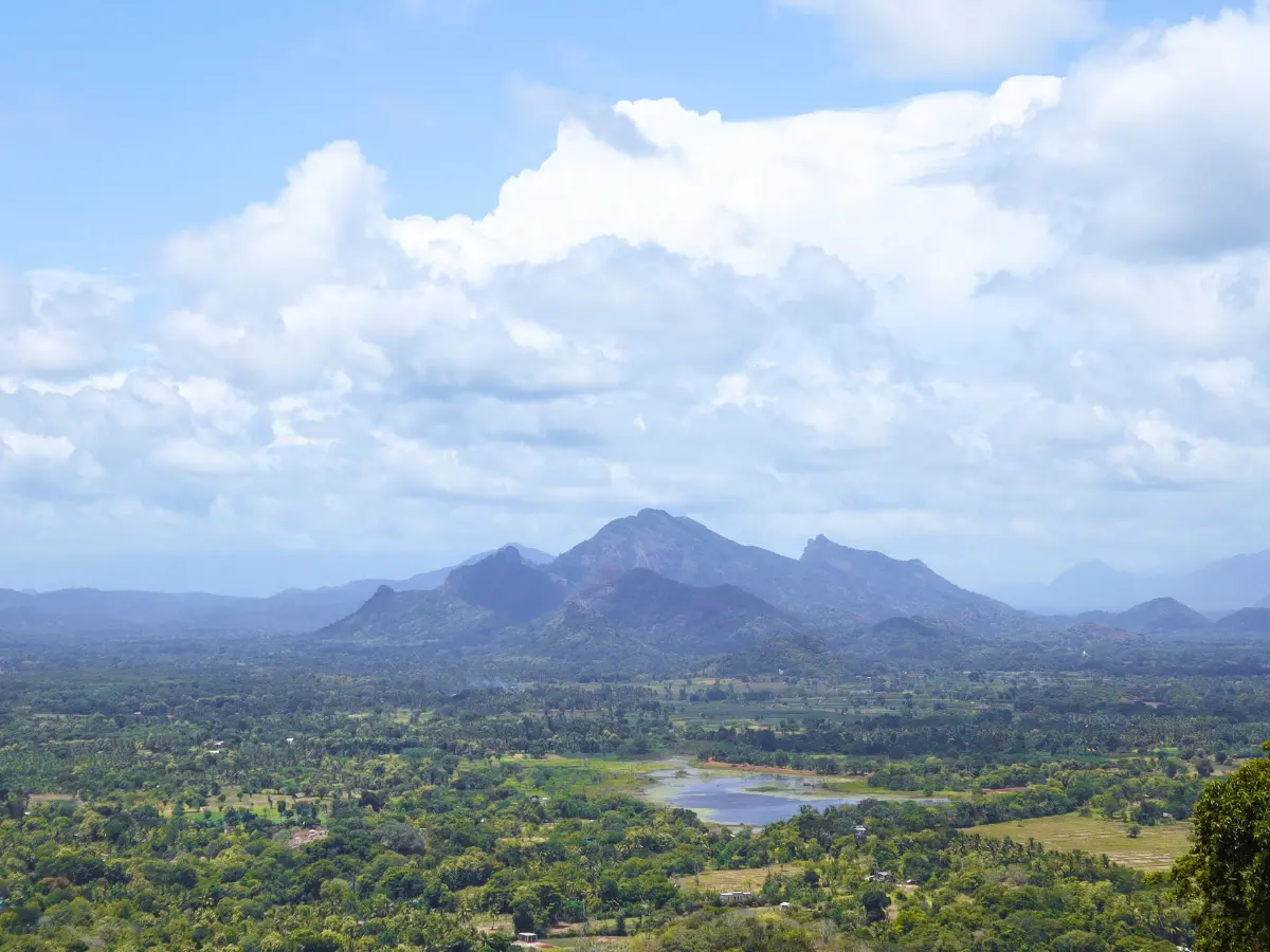 A breathtaking aerial view of the lush green landscapes, lakes, and distant mountains surrounding Sigiriya, Sri Lanka, as seen from the top of Lion Rock