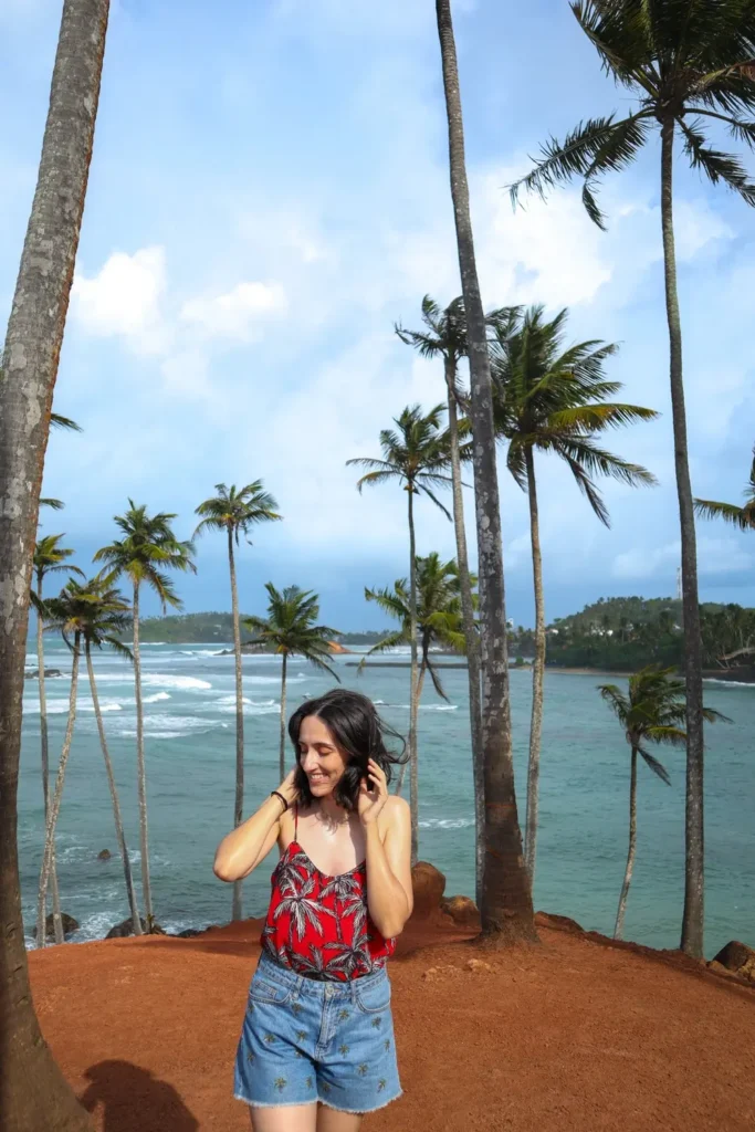 Mariana in a tropical top smiles beneath swaying coconut palms at Coconut Tree Hill, capturing one of the most photogenic things to do in Mirissa.
