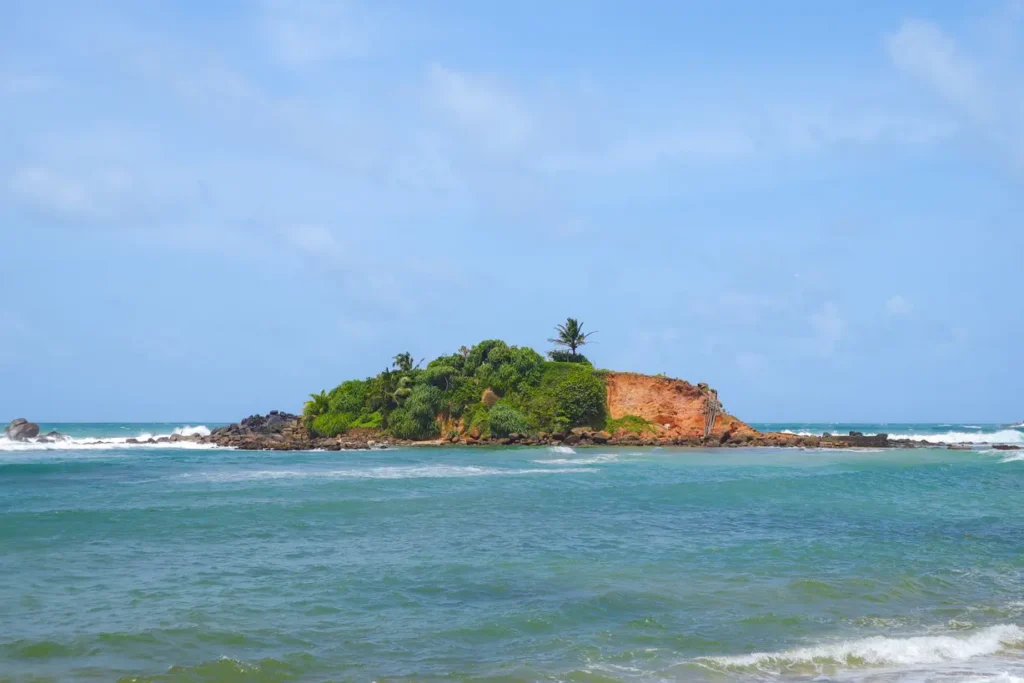 A small rocky island covered in greenery, Parrot Rock is one of the most unique places to visit in Mirissa, offering a short walk across the shallow waters for panoramic beach views.