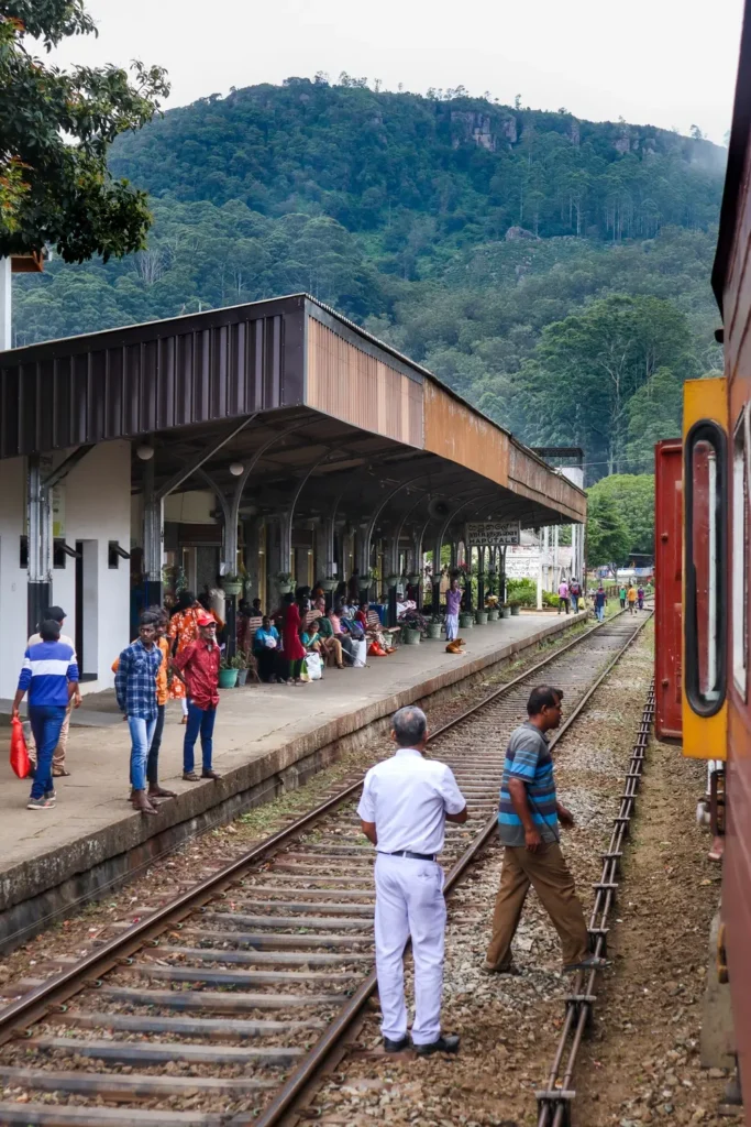 People waiting and chatting at the Haputale train station with forested hills in the background. It’s a charming stop along the popular ella to kandy train route.