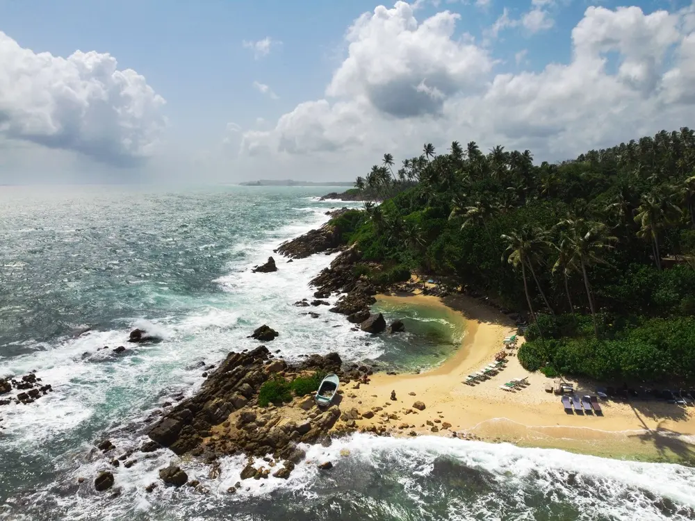Overhead view of the rugged Sri Lankan coastline near Mirissa, with forested cliffs and white waves—ideal for scenic walks and things to do in Mirissa.