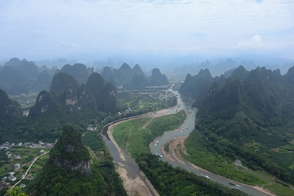 2 weeks in China: the perfect first-timer itinerary for an unforgettable trip 27 Aerial view of the winding Li River cutting through lush green karst mountains near Yangshuo on a hazy day. This scenic spot is a highlight on a China 2 week itinerary for nature lovers.