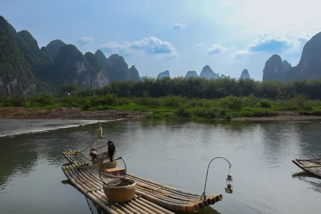 2 weeks in China: the perfect first-timer itinerary for an unforgettable trip 28 Bamboo raft with wicker baskets and cormorant birds floating on the calm Li River, with steep karst peaks in the background. A peaceful moment that reflects local traditions.