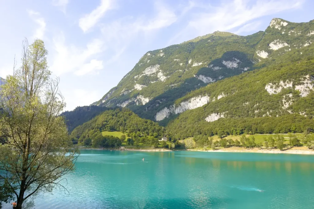 21 locais a visitar no norte de Itália que vos vão conquistar facilmente 20 Crystal-clear waters of Lake Tenno bordered by lush greenery and dramatic alpine cliffs, a serene gem among the top places to visit in Northern Italy.