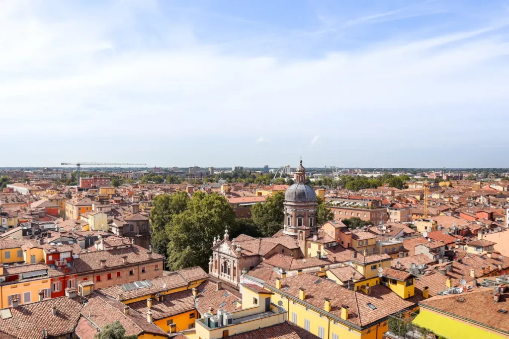 21 locais a visitar no norte de Itália que vos vão conquistar facilmente 26 A panoramic view of Modena featuring a domed church surrounded by terracotta rooftops, one of the culturally rich places to visit in Northern Italy.