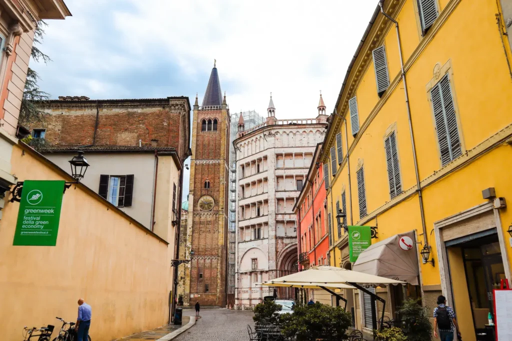 21 locais a visitar no norte de Itália que vos vão conquistar facilmente 27 A cobbled street in Parma framed by vibrant facades and historic towers, capturing the charm of one of the best cities in Northern Italy.