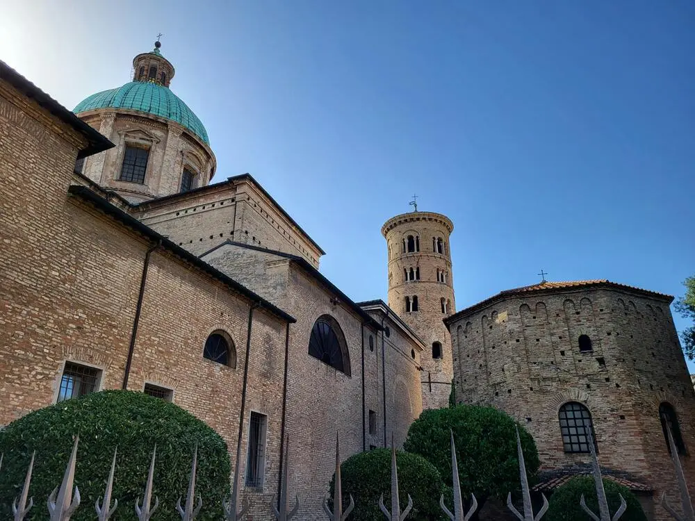 21 beautiful places to visit in Northern Italy that will steal your heart 28 Ancient basilica in Ravenna with a green dome and round bell tower under a clear sky, a standout among historical places to visit in Northern Italy.