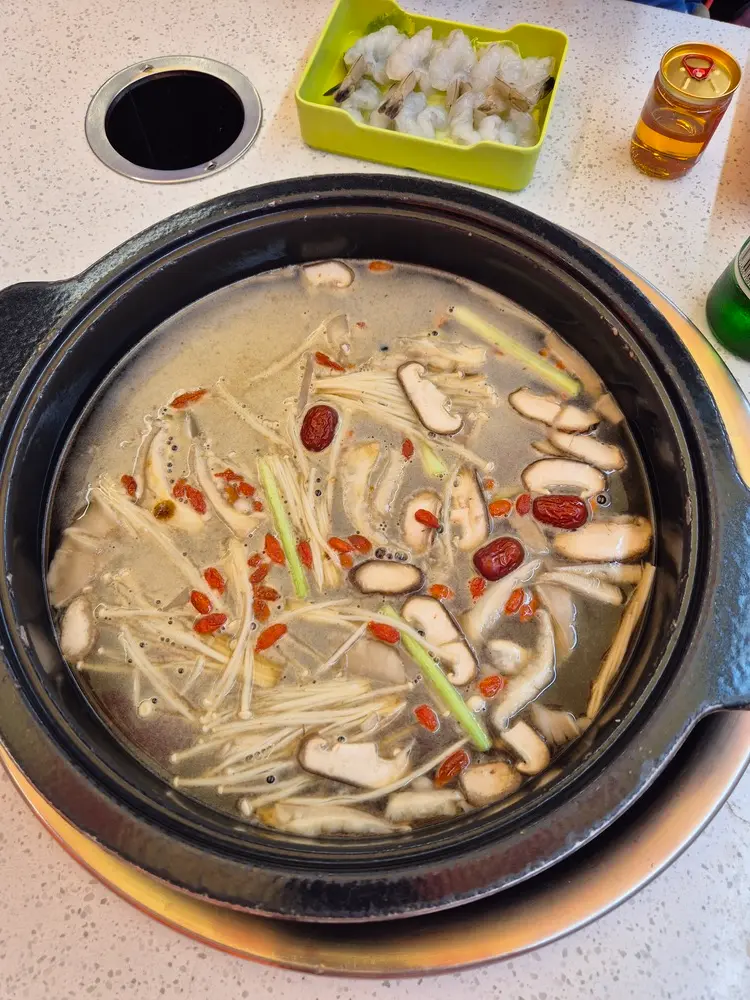 China Travel Tips: 35+ must-know things before visiting (2026 Guide) 19 A bubbling pot filled with mushrooms, goji berries, red dates, and scallions sits at the center of the table.
